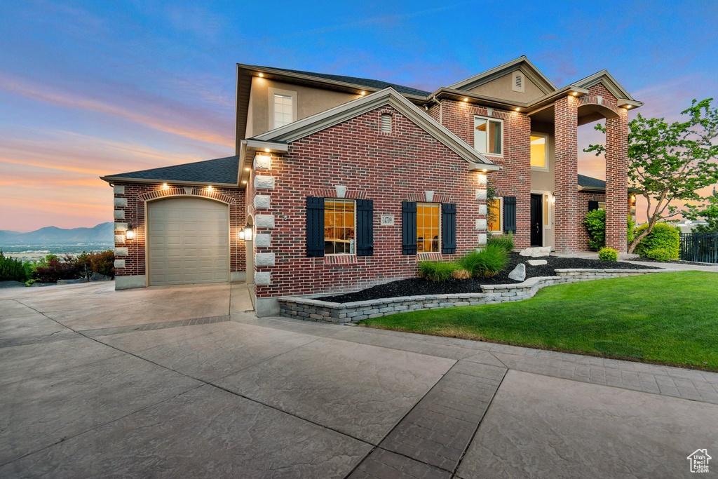 View of front of property featuring concrete driveway, brick siding, a front yard, and an attached garage