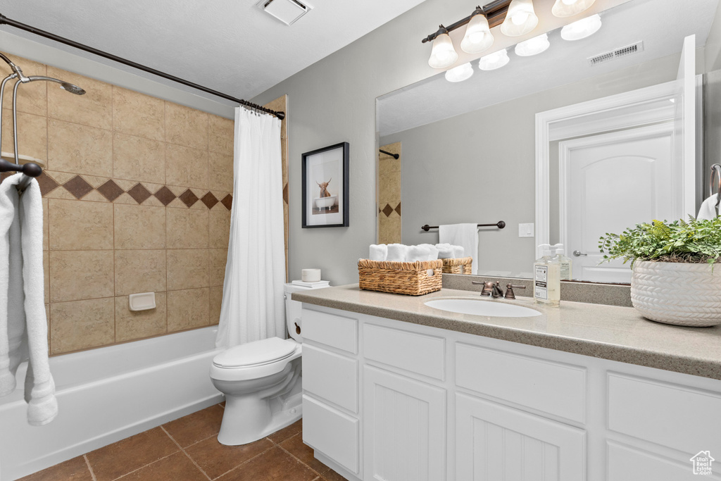 Bathroom featuring vanity, tile patterned floors, toilet, and shower / bathtub combination with curtain