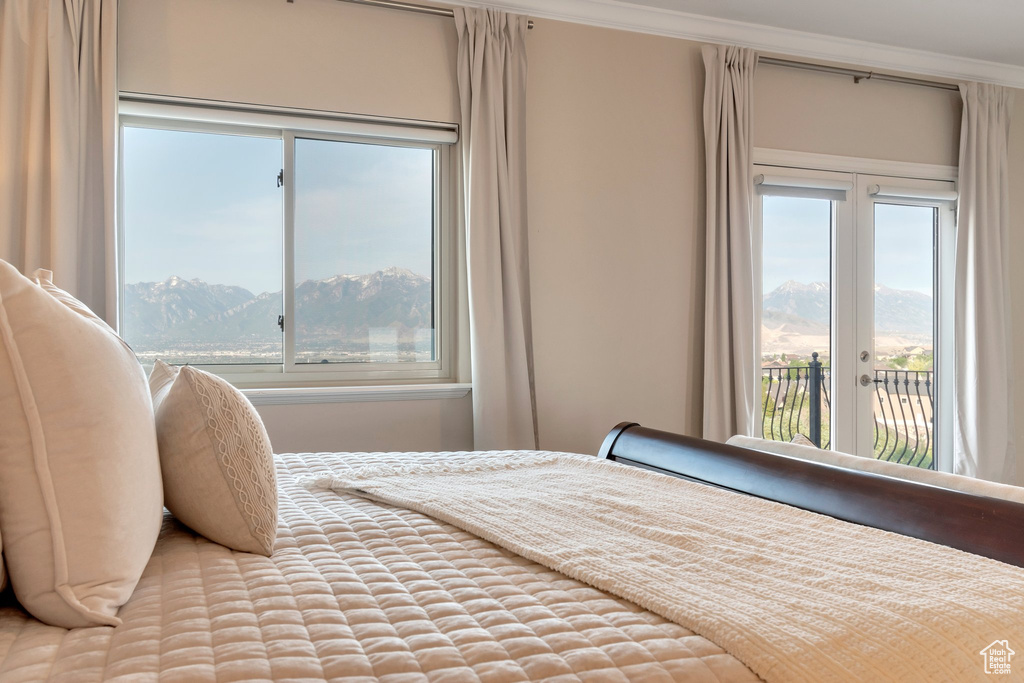 Bedroom featuring access to outside, a mountain view, multiple windows, and crown molding