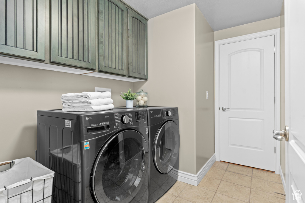 Washroom featuring cabinet space, independent washer and dryer, baseboards, and light tile patterned flooring