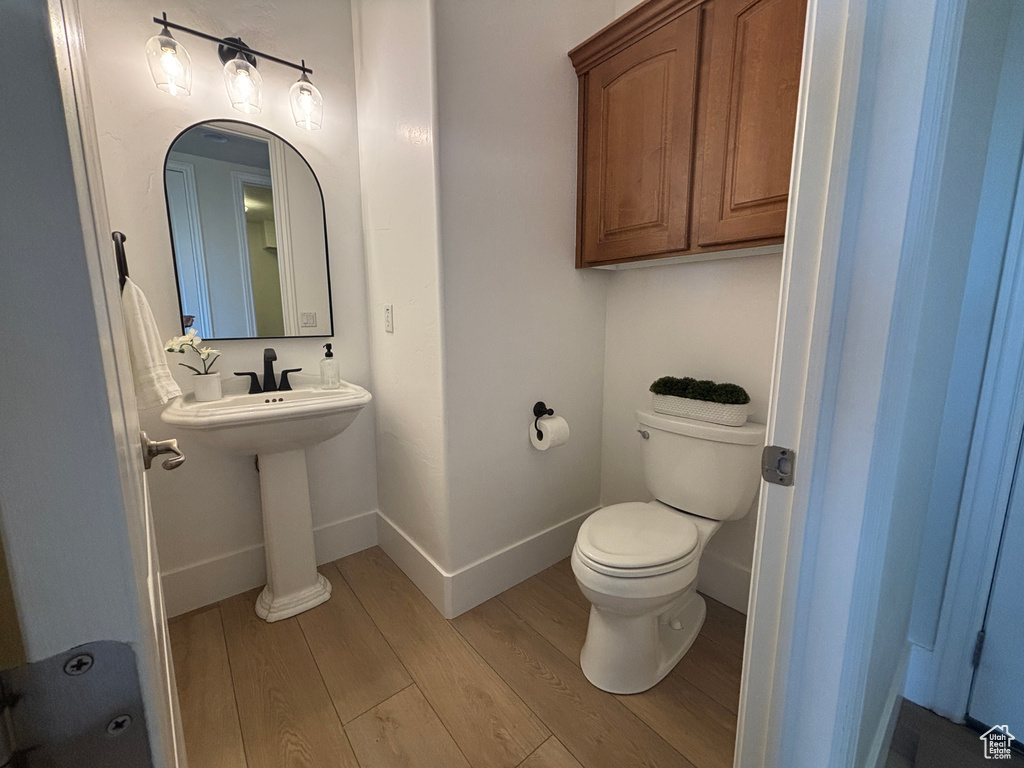 Bathroom with wood finished floors, toilet, and baseboards