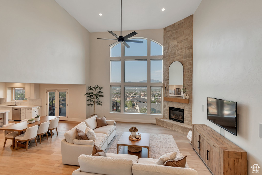 Living room featuring high vaulted ceiling, a fireplace, a ceiling fan, light wood finished floors, and recessed lighting