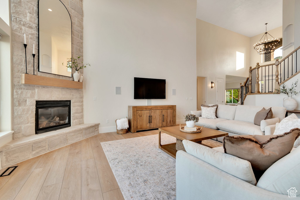 Living room with a high ceiling, hardwood / wood-style floors, stairway, baseboards, and a fireplace