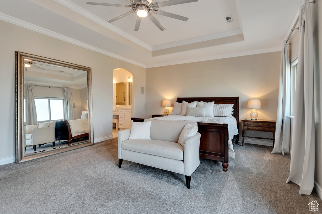 Bedroom featuring a tray ceiling, carpet floors, ornamental molding, arched walkways, and baseboards