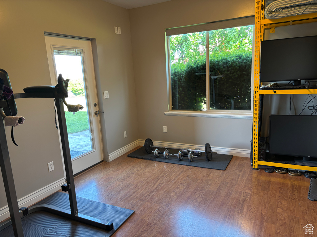 Exercise area featuring wood finished floors, healthy amount of natural light, and baseboards
