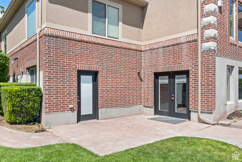 Back of property featuring french doors, brick siding, and a patio area