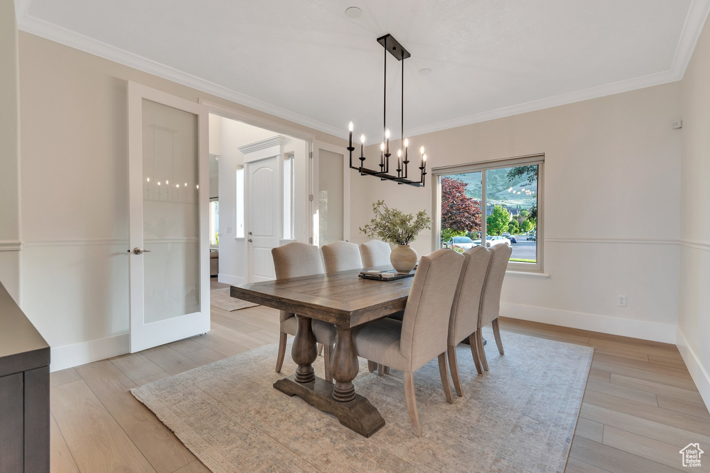 Dining area featuring a chandelier, light wood-type flooring, ornamental molding, and baseboards