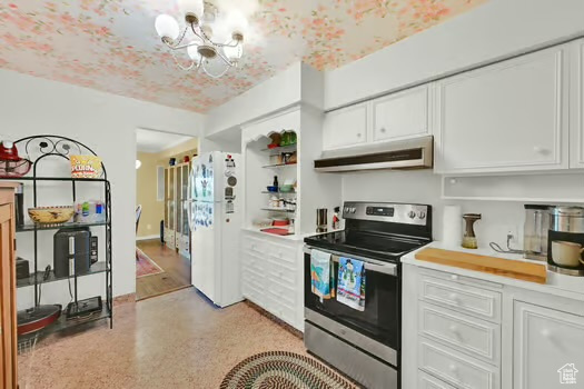 Kitchen with under cabinet range hood, stainless steel electric stove, freestanding refrigerator, white cabinetry, and light countertops