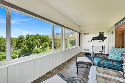 Sunroom / solarium with an outdoor hangout area and stone finish flooring