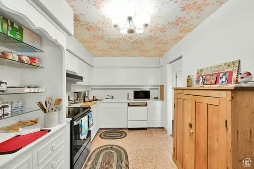Kitchen featuring white appliances, light countertops, under cabinet range hood, white cabinetry, and a sink