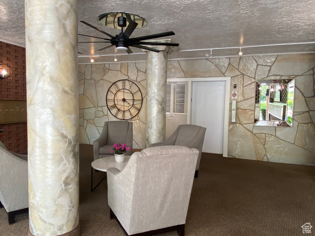 Carpeted living room with ornate columns and a ceiling fan