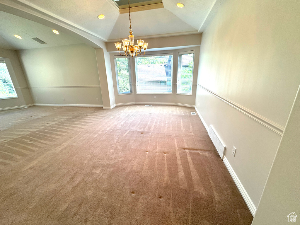Spare room featuring a chandelier, light colored carpet, vaulted ceiling, baseboards, and recessed lighting