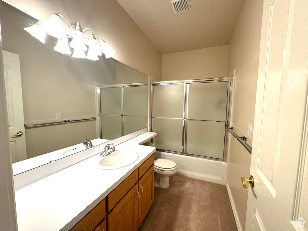 Bathroom featuring vanity, toilet, and bath / shower combo with glass door