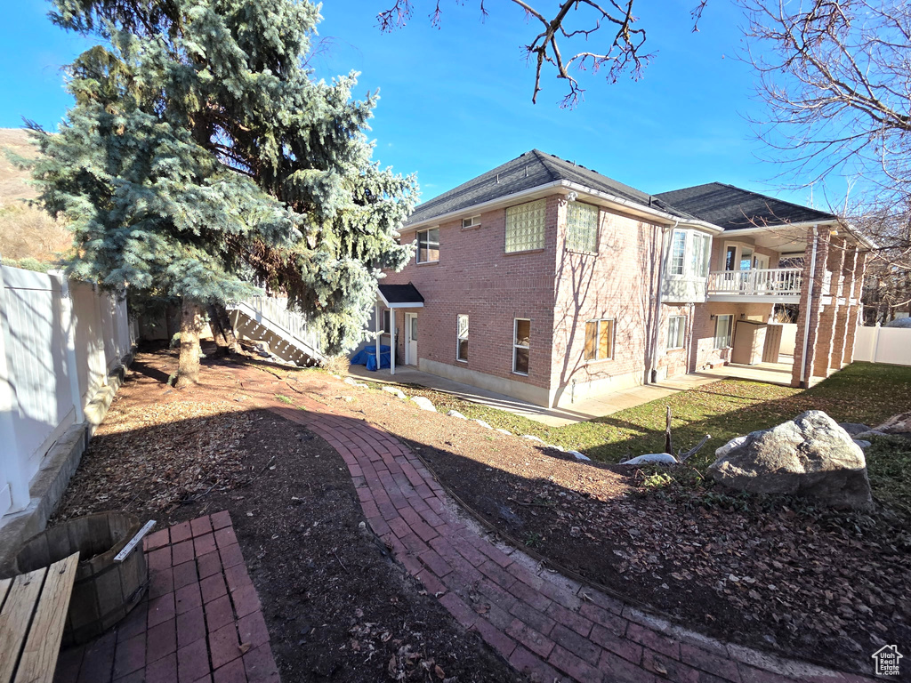 View of home's exterior featuring a balcony, a fenced backyard, brick siding, a patio area, and stairway