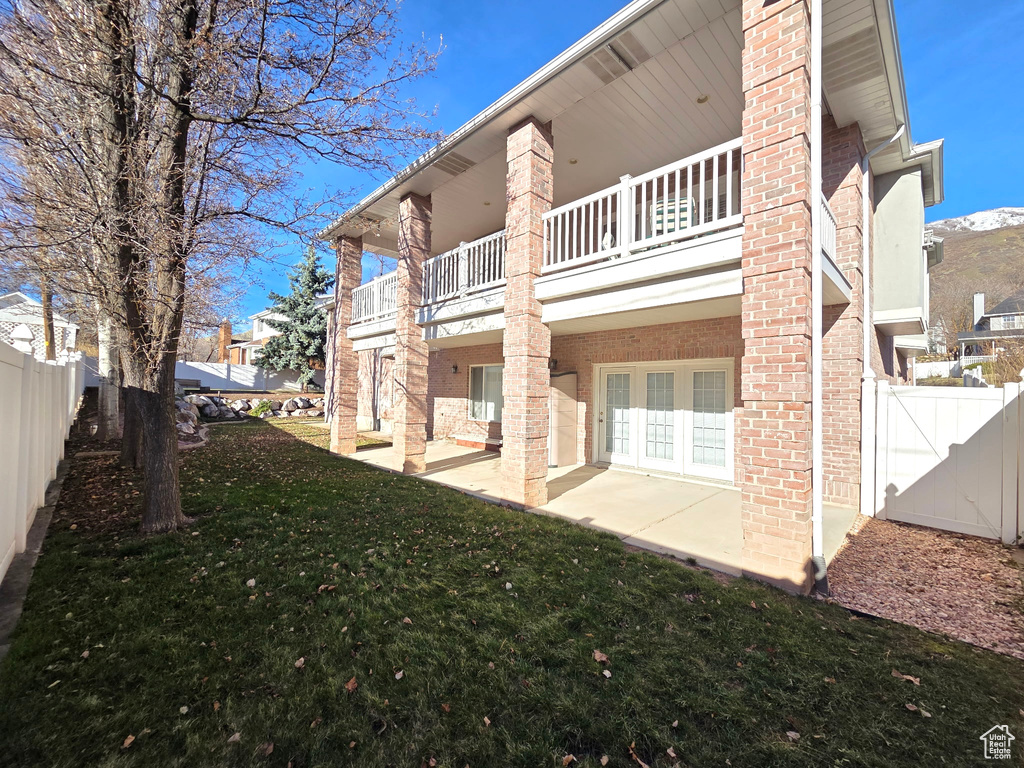 Rear view of property with a balcony, a patio, and brick siding