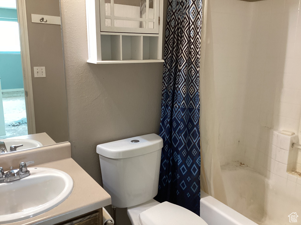Bathroom with toilet, shower / bath combo, and vanity