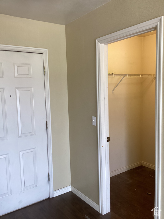 Unfurnished bedroom featuring wood finished floors, a closet, a spacious closet, and baseboards