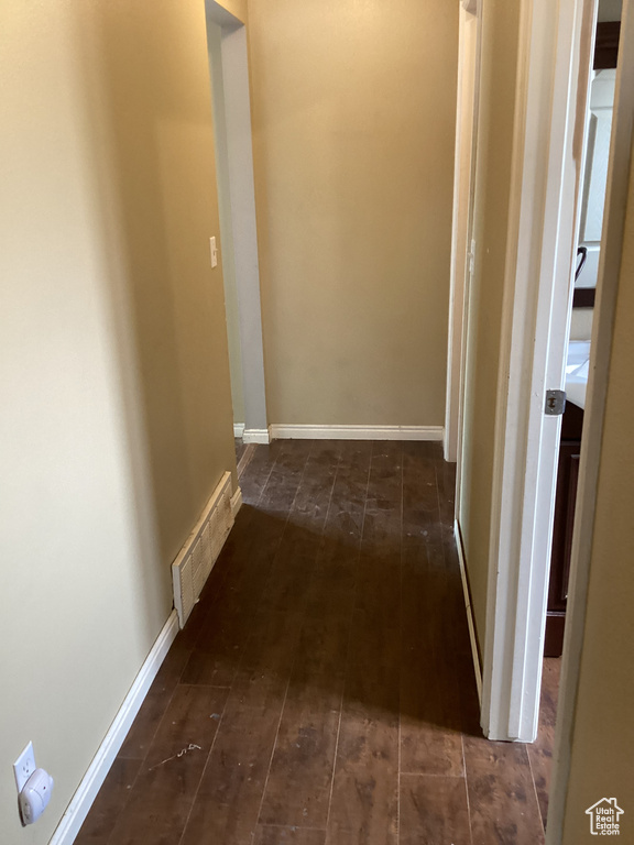 Hallway featuring dark wood-style flooring and baseboards
