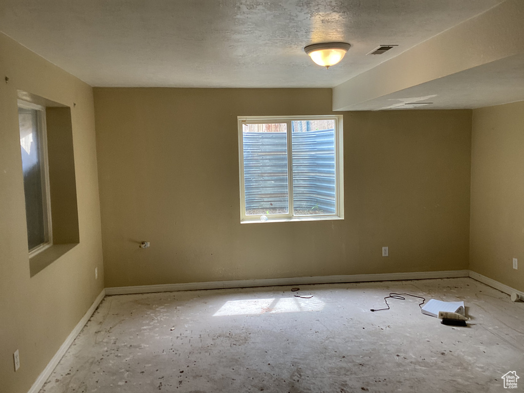 Empty room featuring baseboards and a textured ceiling
