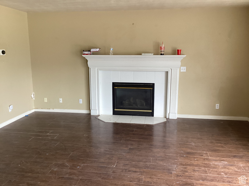 Unfurnished living room featuring wood finished floors, a fireplace, and baseboards
