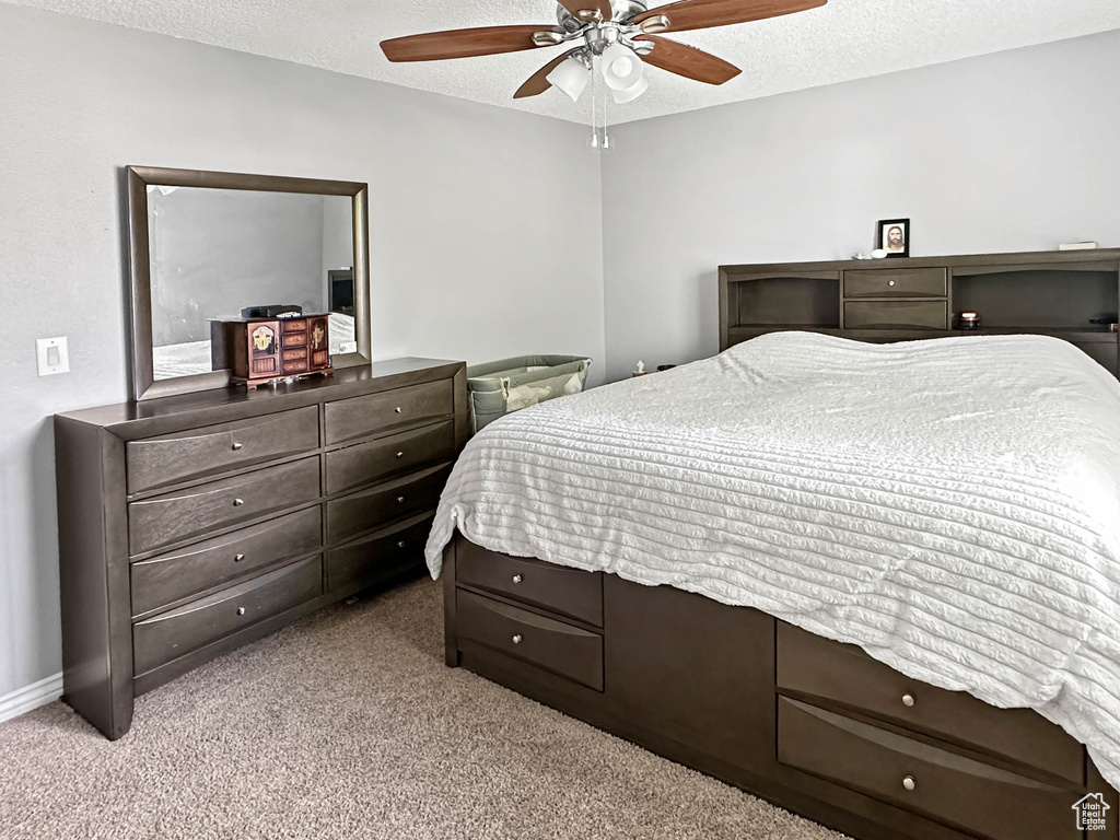 Bedroom with light colored carpet, a textured ceiling, ceiling fan, and baseboards