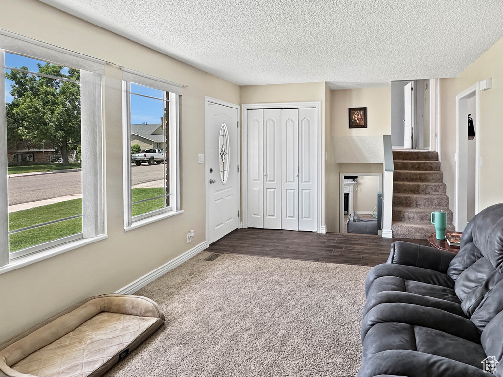 Living area featuring dark colored carpet, baseboards, stairs, and a textured ceiling