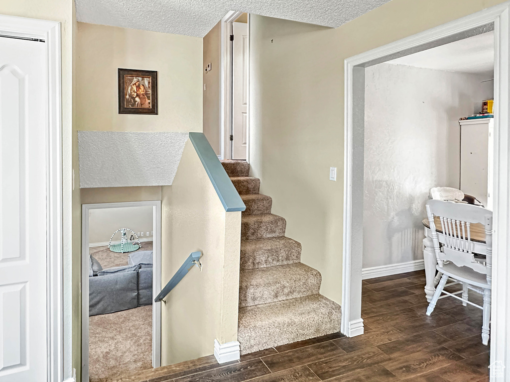 Staircase featuring wood finished floors, a textured ceiling, and baseboards