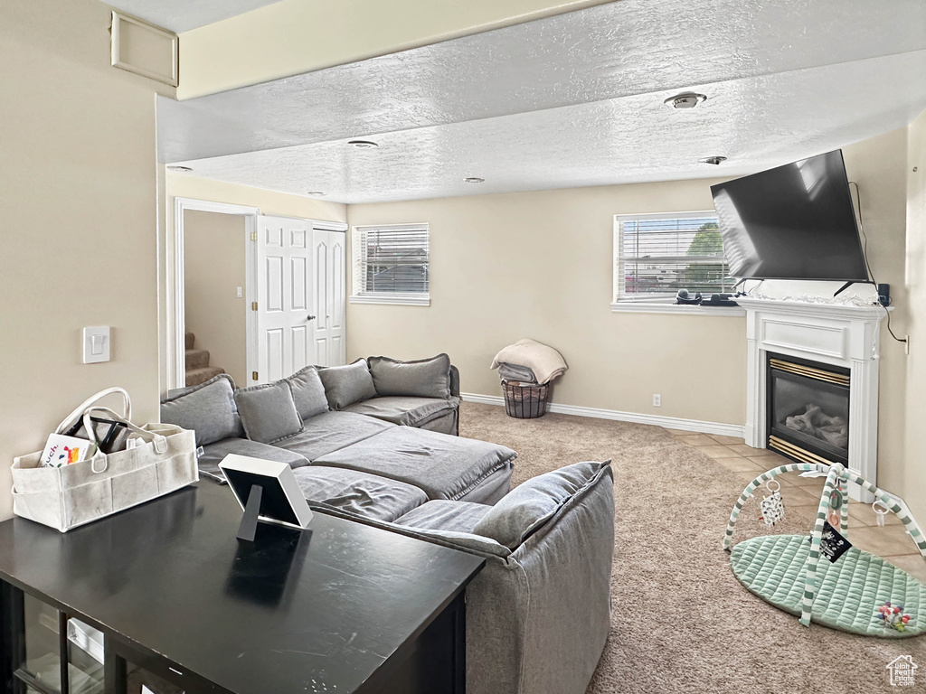 Carpeted living area featuring a glass covered fireplace, a textured ceiling, and baseboards