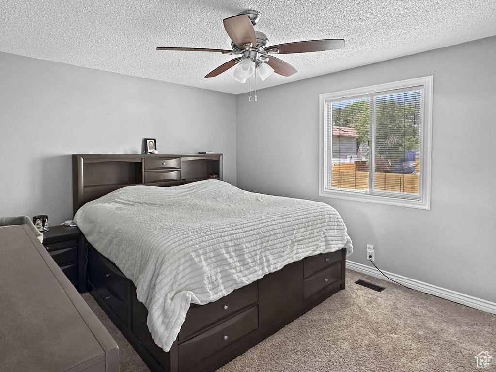 Carpeted bedroom with a textured ceiling, baseboards, and ceiling fan
