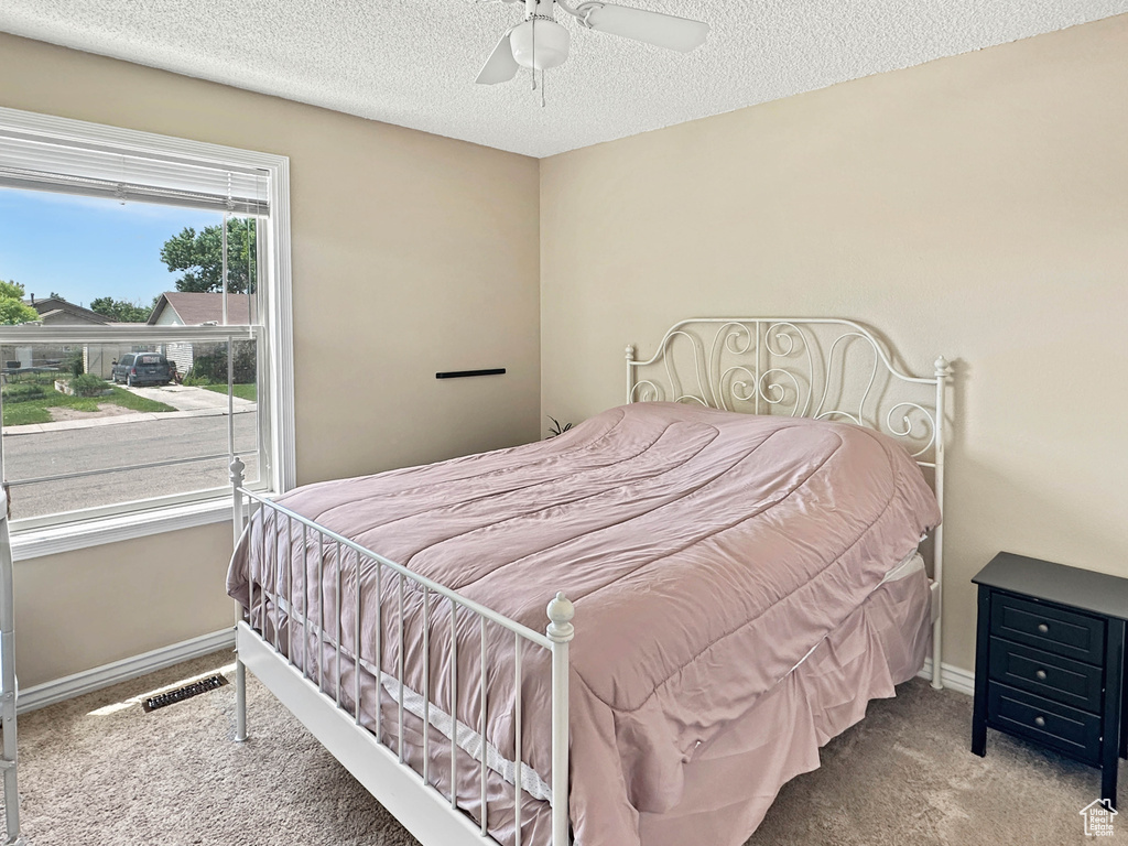 Bedroom featuring carpet flooring, a textured ceiling, baseboards, and a ceiling fan