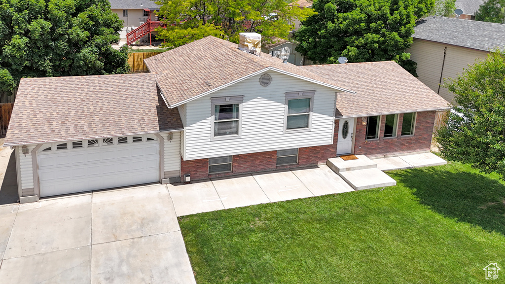 Tri-level home featuring a shingled roof, concrete driveway, brick siding, and a garage