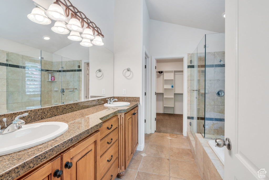 Full bath with a shower stall, double vanity, a spacious closet, and tile patterned floors