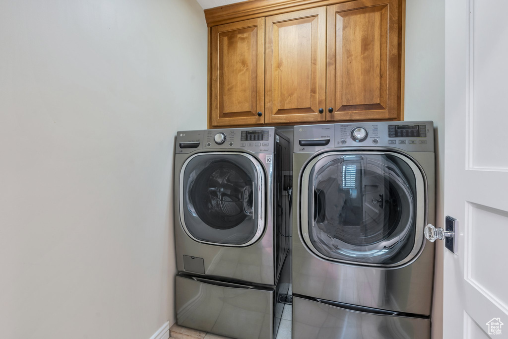 Laundry room with washing machine and dryer, cabinet space, and baseboards