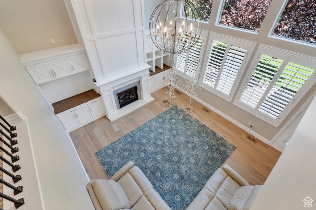 Living room featuring wood finished floors, a chandelier, stairs, a fireplace, and baseboards