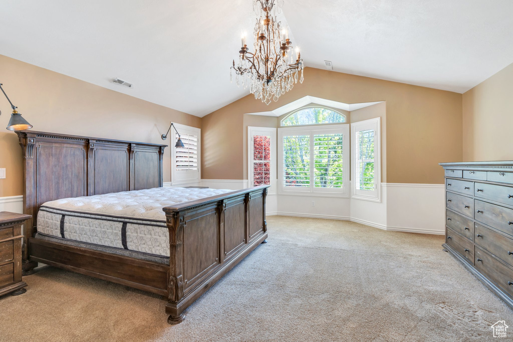 Bedroom with a chandelier, light carpet, vaulted ceiling, and baseboards