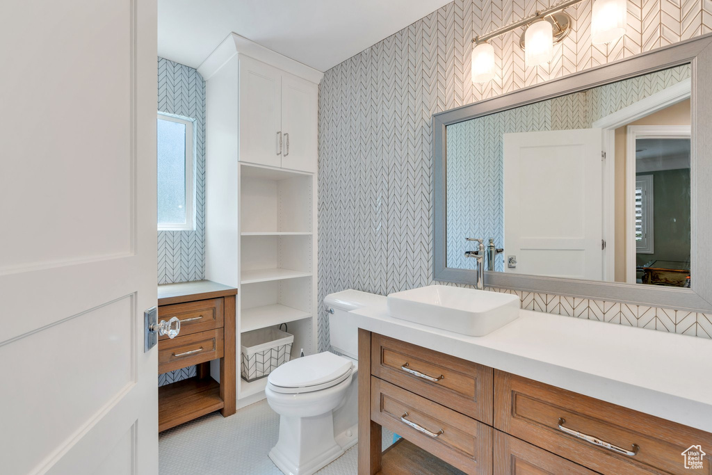 Bathroom featuring wallpapered walls, vanity, and toilet