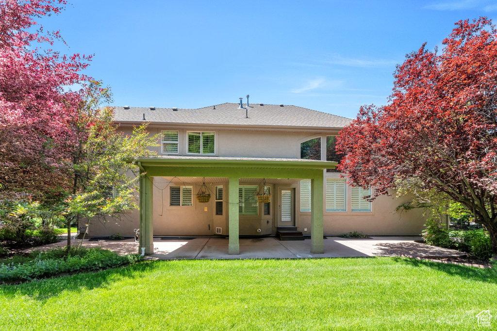 Rear view of house featuring stucco siding, a patio area, a yard, and entry steps
