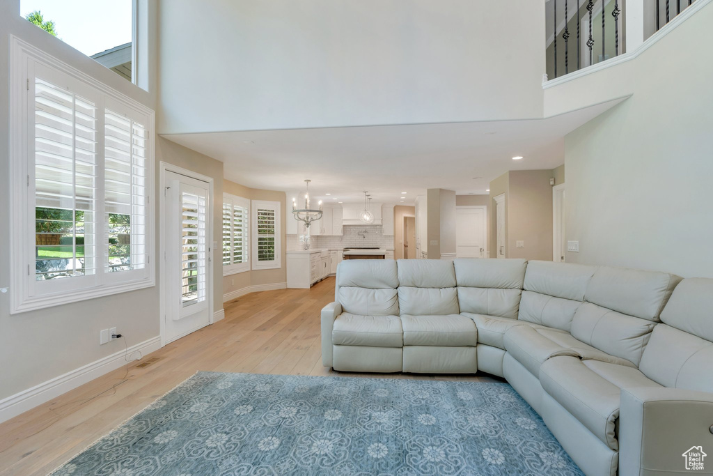 Living area featuring light wood finished floors, a high ceiling, a chandelier, healthy amount of natural light, and recessed lighting