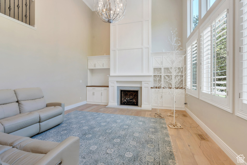 Living area with a high ceiling, a chandelier, wood finished floors, healthy amount of natural light, and baseboards
