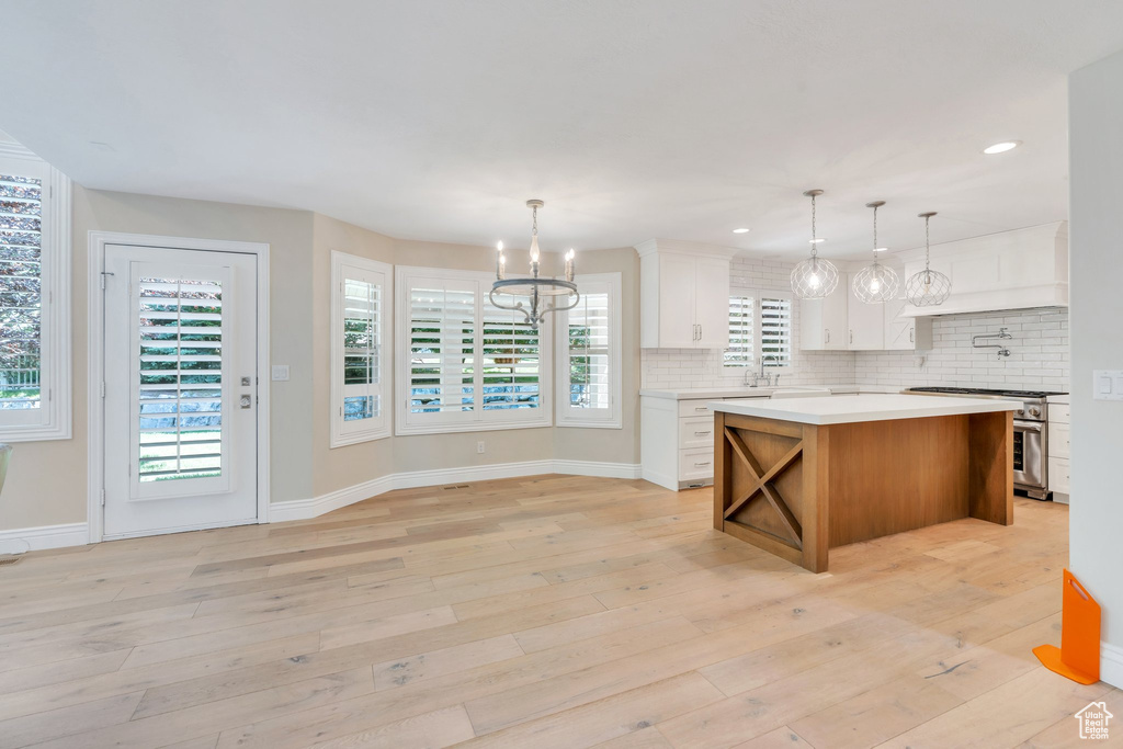 Kitchen with high end stainless steel range, a chandelier, light countertops, decorative backsplash, and white cabinetry