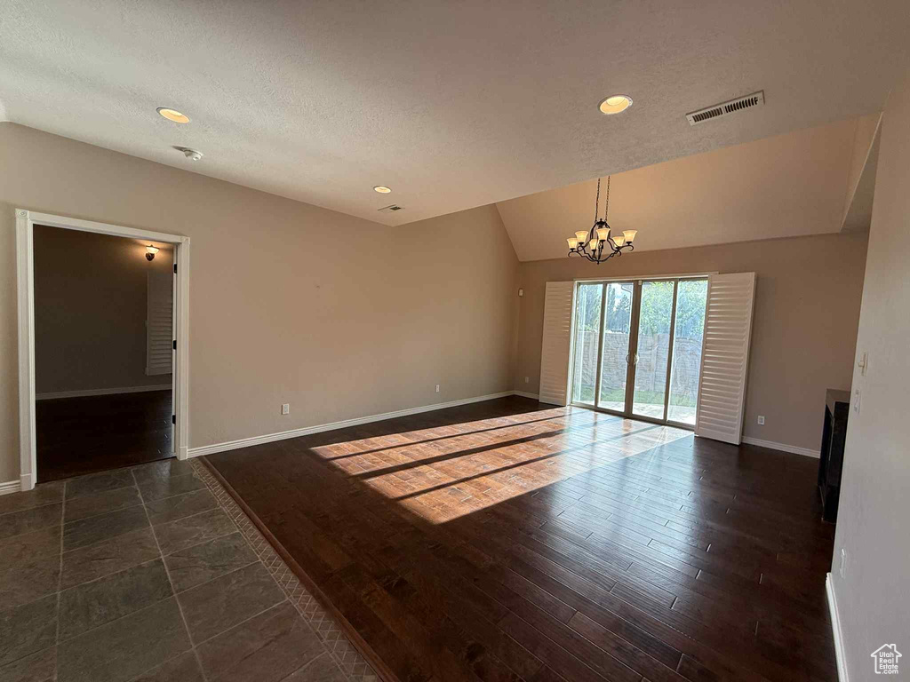Spare room with a chandelier, baseboards, lofted ceiling, a textured ceiling, and recessed lighting