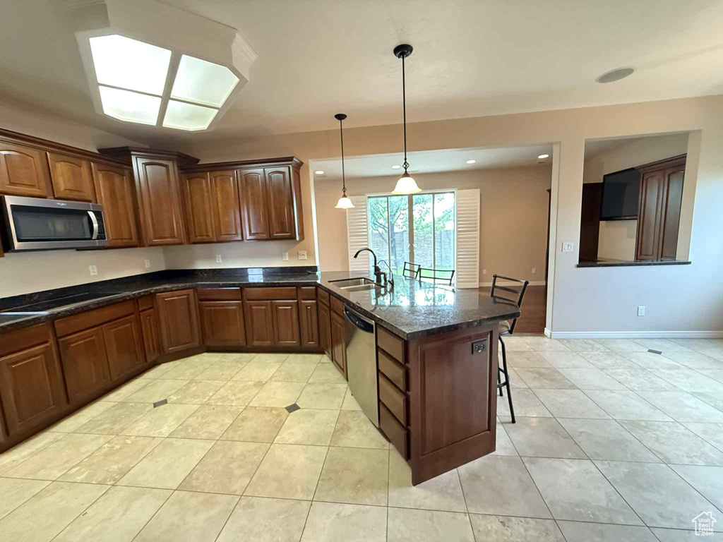 Kitchen featuring stainless steel appliances, a sink, a peninsula, a breakfast bar area, and light tile patterned floors