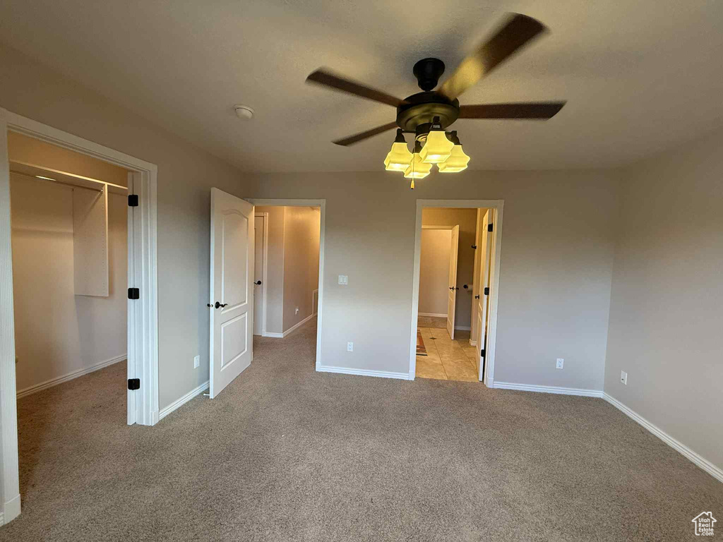 Unfurnished bedroom with light colored carpet, baseboards, a closet, and a ceiling fan