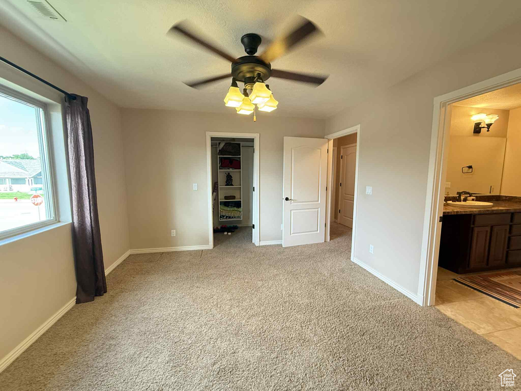 Unfurnished bedroom with a sink, light carpet, baseboards, and connected bathroom