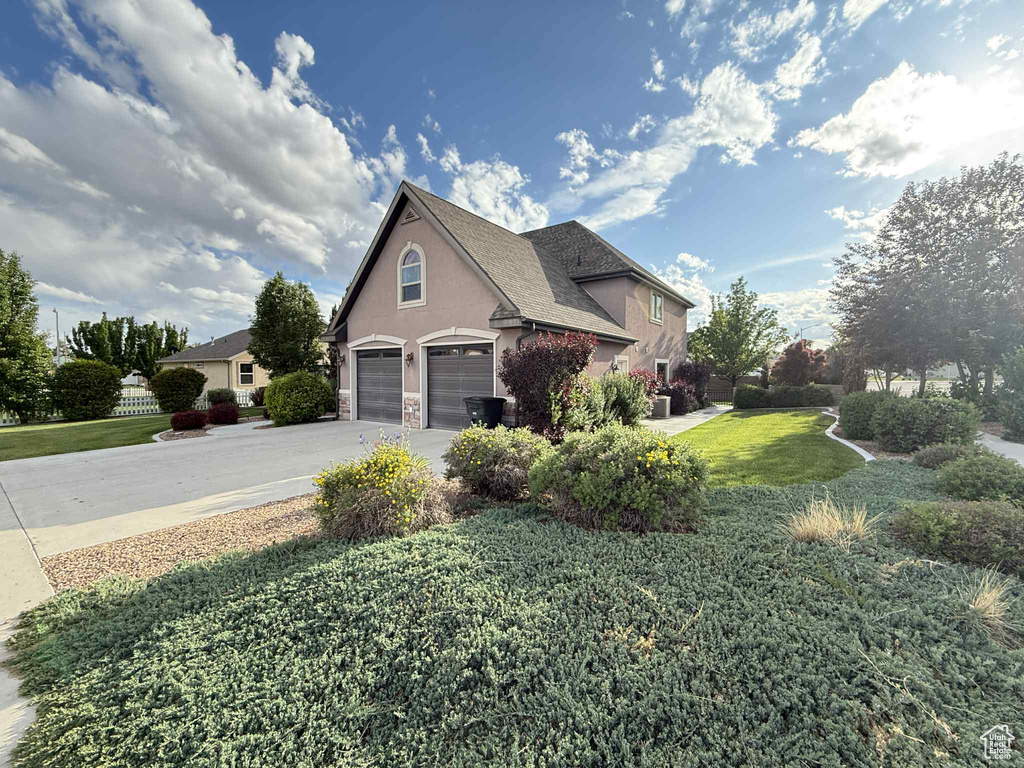 View of home's exterior featuring stucco siding, a yard, driveway, stone siding, and an attached garage
