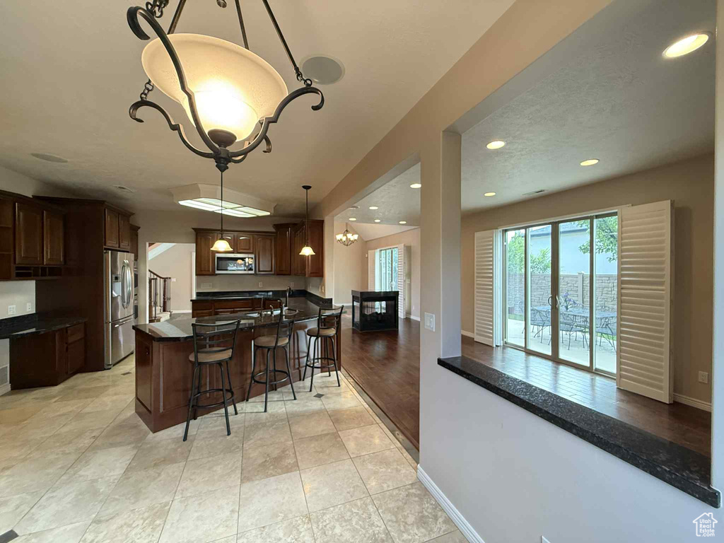 Kitchen featuring appliances with stainless steel finishes, a breakfast bar area, a chandelier, recessed lighting, and dark countertops