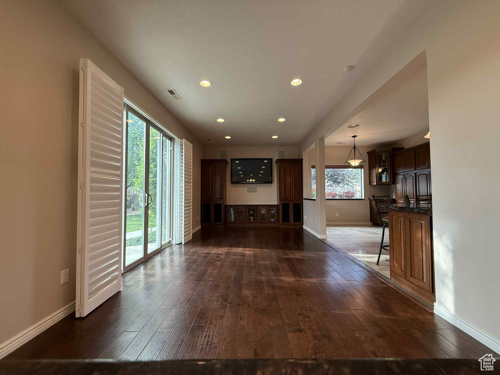 Unfurnished living room featuring plenty of natural light, dark wood-style flooring, baseboards, and recessed lighting