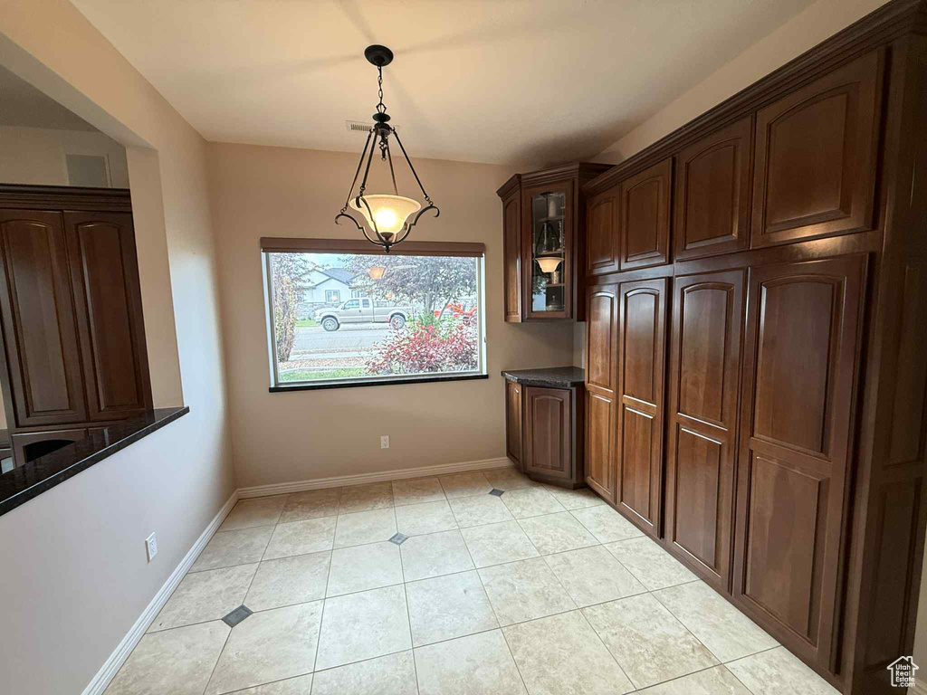 Unfurnished dining area featuring baseboards and light tile patterned flooring