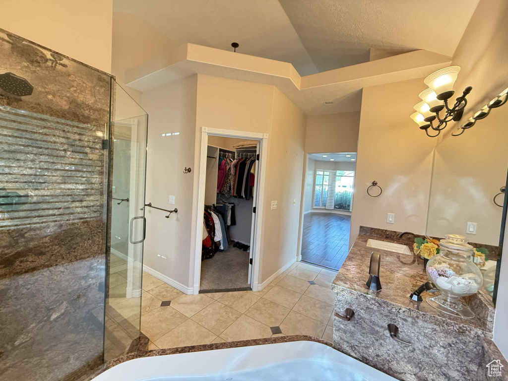 Full bath featuring a shower stall, tile patterned floors, a spacious closet, double vanity, and vaulted ceiling