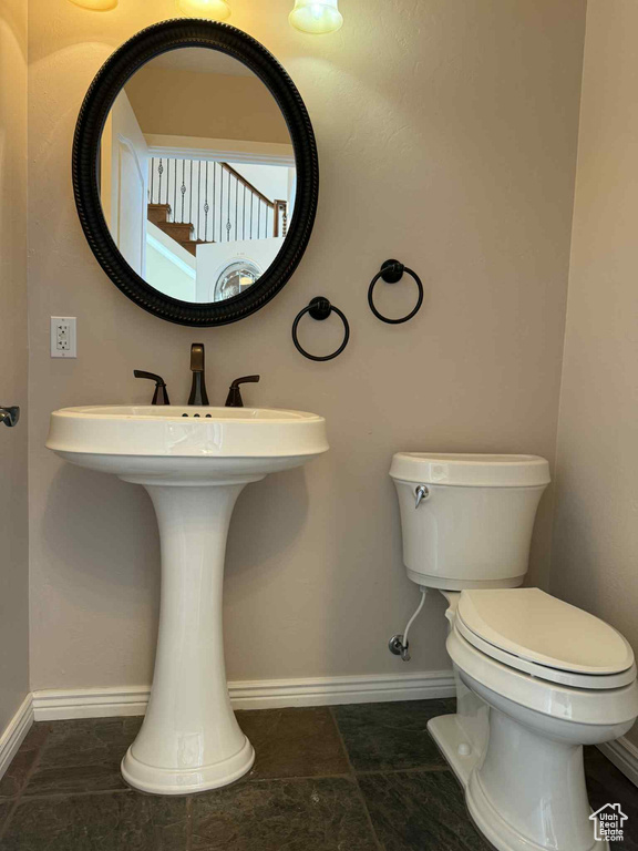 Half bathroom featuring toilet, baseboards, and a sink